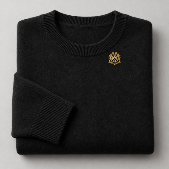Black cashmere crew-neck sweater with small gold crest above the heart